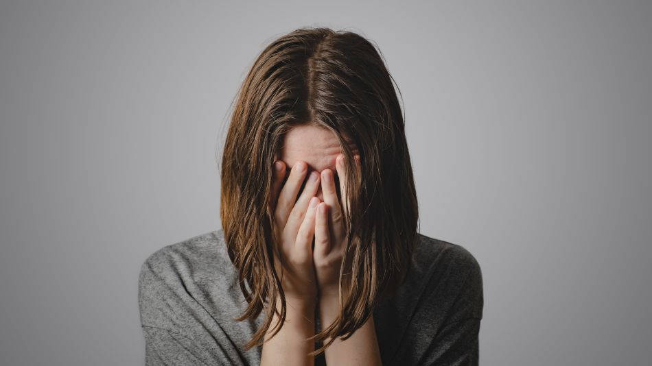 traumatización vicaria- mujer triste se cubre la cara con las manos